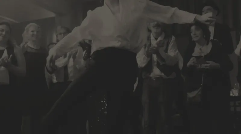 Un ballerino in camicia bianca a braccia aperte davanti al pubblico